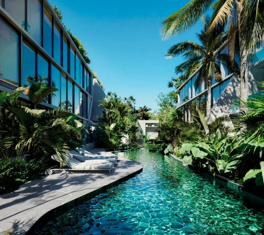 Piscina estreita e comprida entre duas alas envidraçadas de um edifício baixo, cercada de palmeiras e vegetação densa, com espreguiçadeiras na borda.