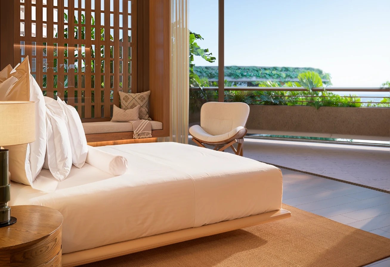 Suíte de uma residência do Tempo com cama de casal, painel de madeira e varanda com vista para a vegetação